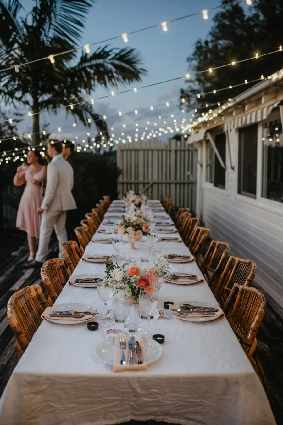 Pareja de novios junto a una mesa larga de banquete preparada al anochecer